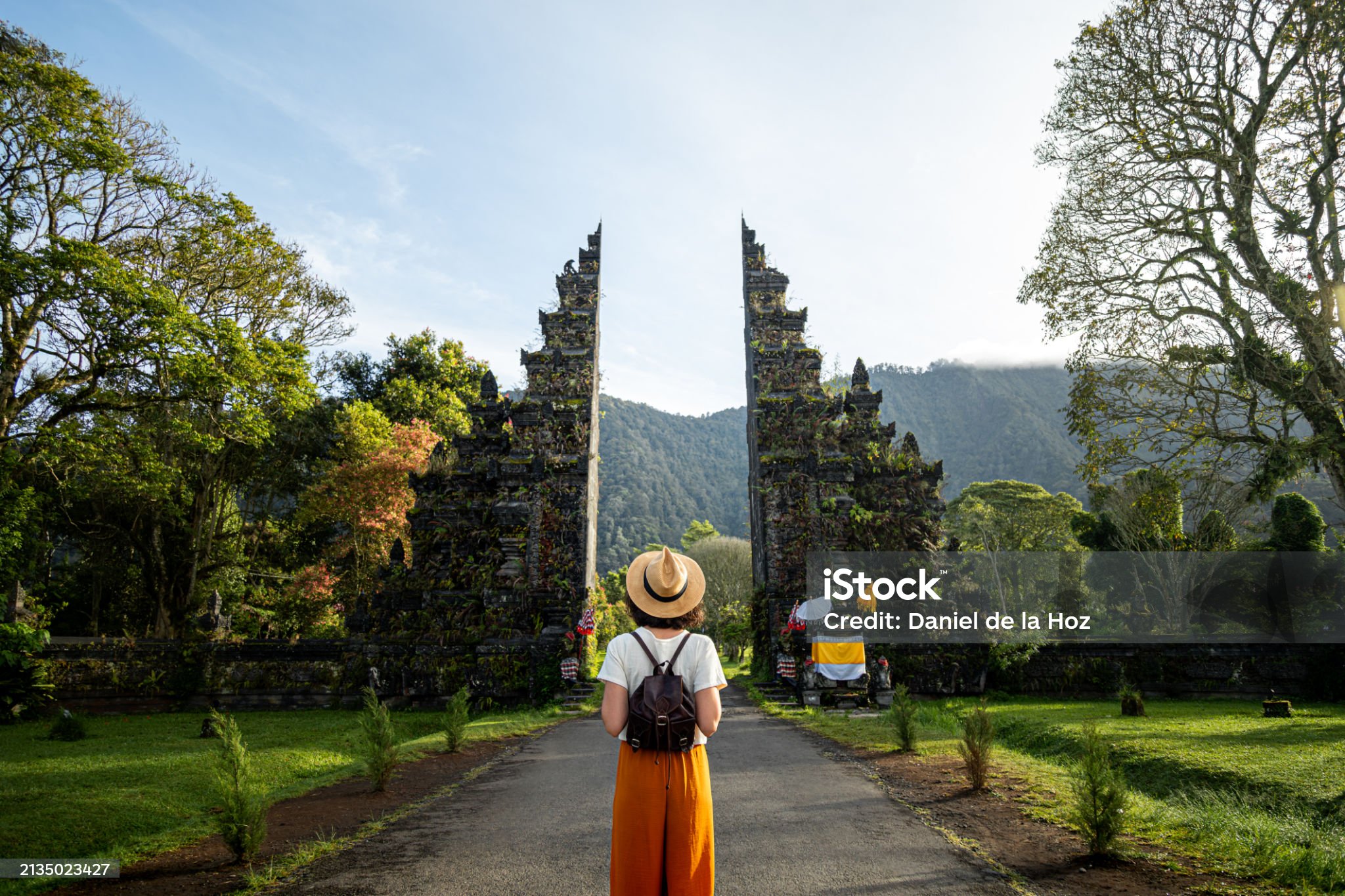 Woman tourist traveler with backpack enjoying walk through Balinese Hindu temple during vacation in Asia. Woman contemplating monument during holidays. Copy space. Traveling in Asia concept.